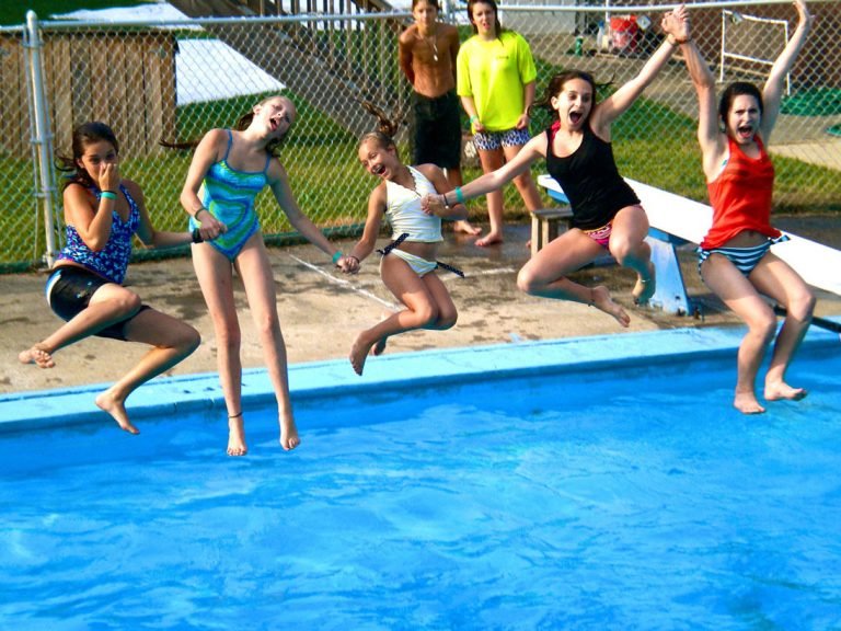 Five girls hold hands and jump into the pool