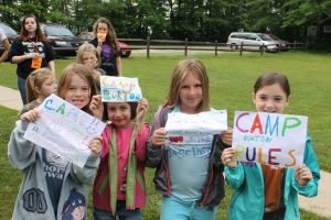 four girls with camp burton signs they drew