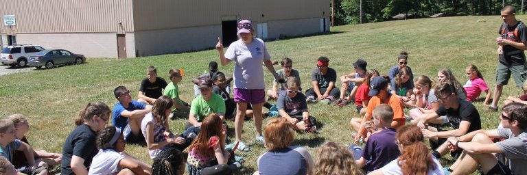 Circle of kids listening to a camp leader