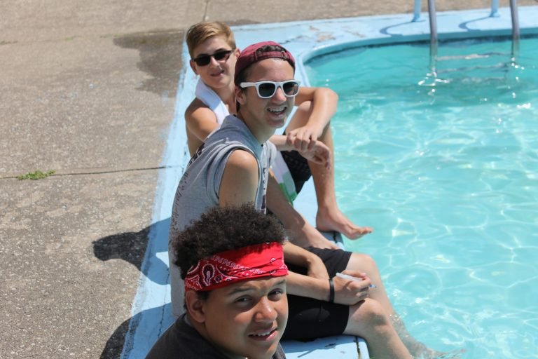 Teen boys sitting on the side of the pool at camp burton